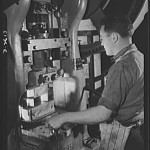 Conversion. Toy factory. Skillfully operating this massive press, a worker stamps out part of a filter box essential to the armed forces. Before conversion of this machine, metal toys were stamped out. The change over consisted chiefly of new dies. Keystone
